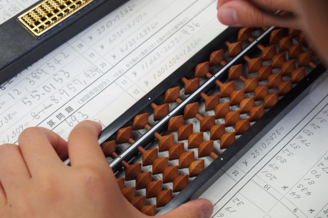 プリントの上でそろばんを使って計算する様子